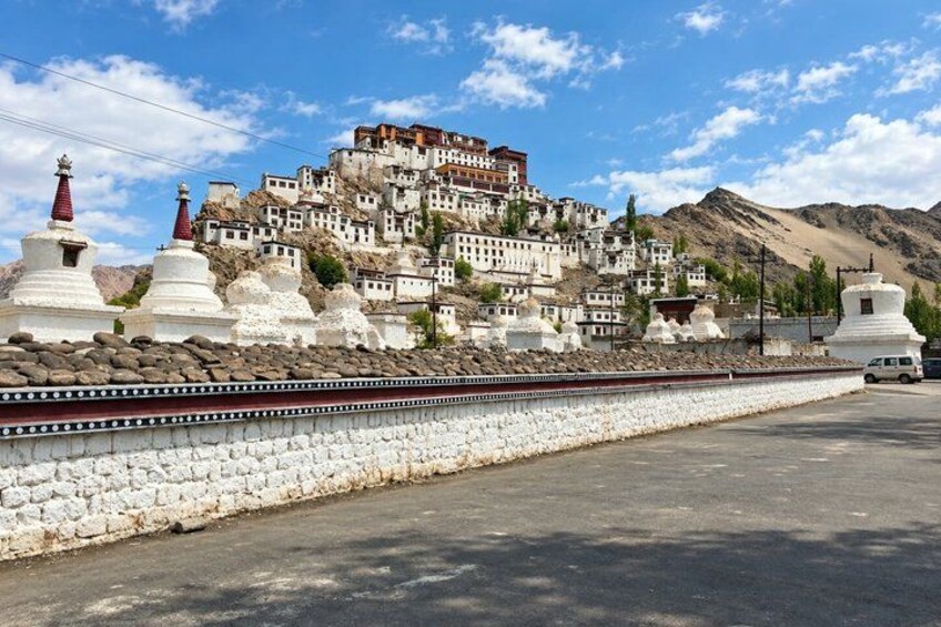 A mountainous monastery with white stupas and a clear sky. 4