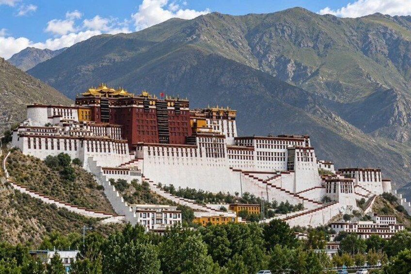 A large, multi-tiered monastery complex with a prominent golden spire, surrounded by mountainous terrain. 3