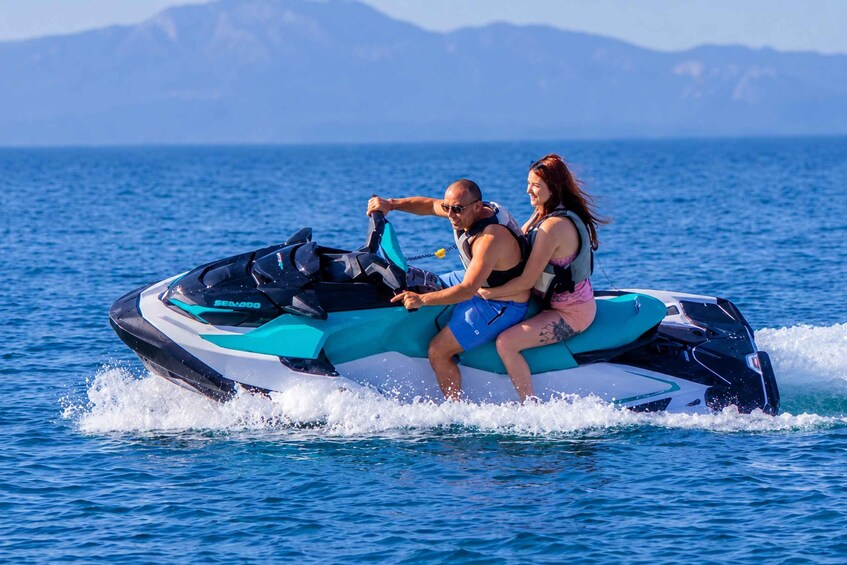 Zwei Personen auf einem Jetski vor einer gebirgigen Landschaft. 1