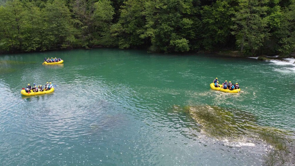 Drei gelbe Luftmatratzen auf einem ruhigen Fluss, umgeben von dichtem Grünwald. 3