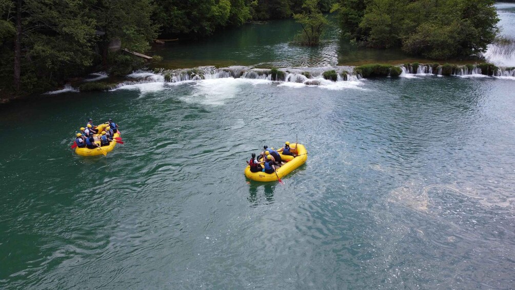 Zwei gelbe Luftmatratzen auf einem Fluss mit einem Wasserfall im Hintergrund. 5