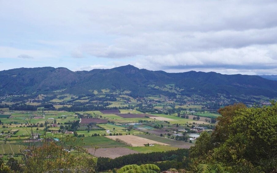 A valley with fields, a small town, and mountains in the background. 2