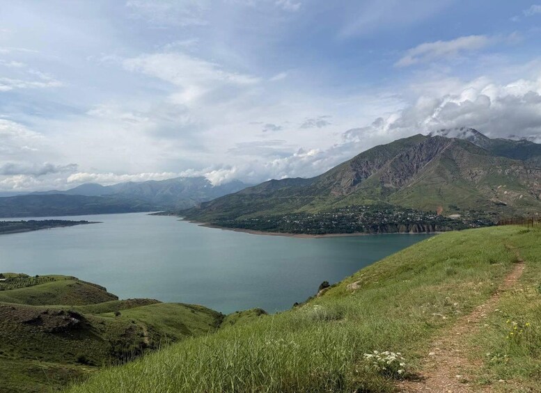 Un lac entouré de montagnes, un ciel dégagé et un sentier bordé d’herbe. 3
