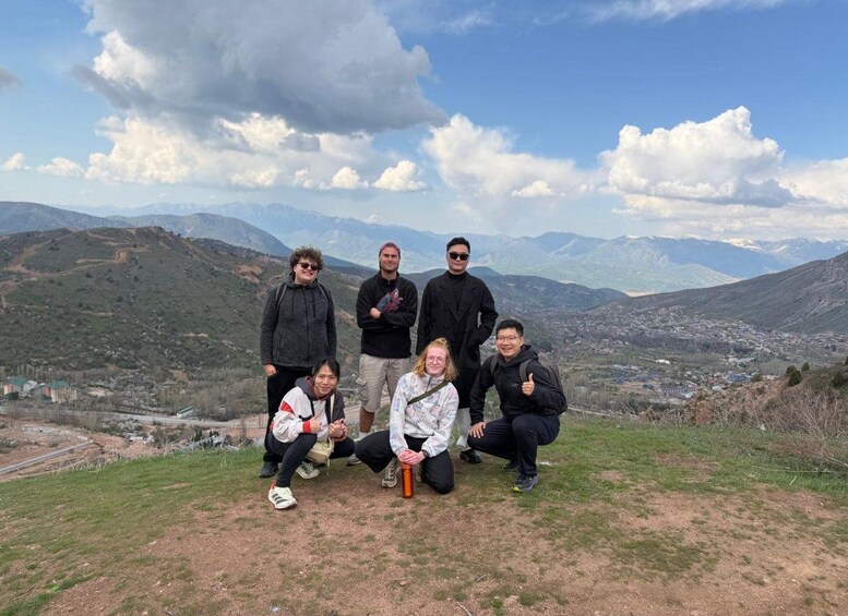Un groupe de personnes se trouve sur une colline herbeuse, avec un paysage montagneux en arrière-plan. 5
