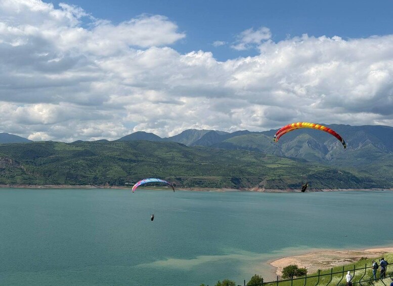 Une personne pratiquant le parapente au-dessus d’un lac, avec des montagnes en arrière-plan. 4