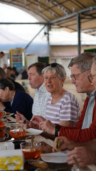 Des personnes dînent lors d’un événement en plein air, autour de tables et en dégustant des plats. 2