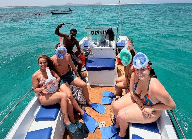 Eine Gruppe von Menschen in einem Boot mit Tauchausrüstung, ein klares blaues Meer und eine entfernte Küstenlinie. 5