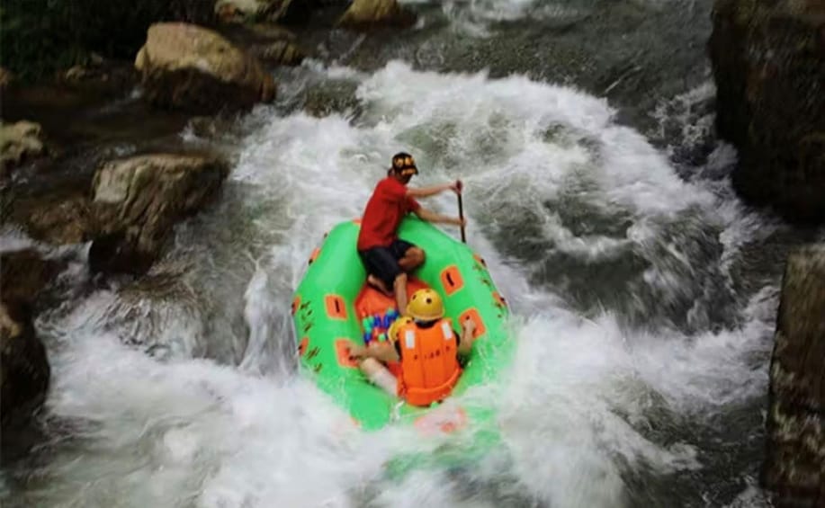 A person in a green inflatable raft navigating a river with white water rapids. 2