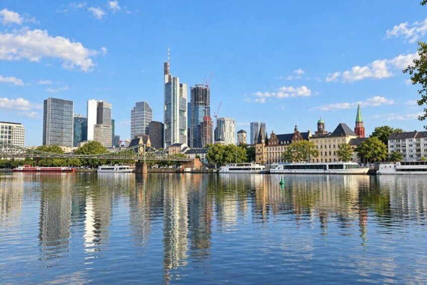 A city skyline with modern buildings and a river reflecting the structures. 2
