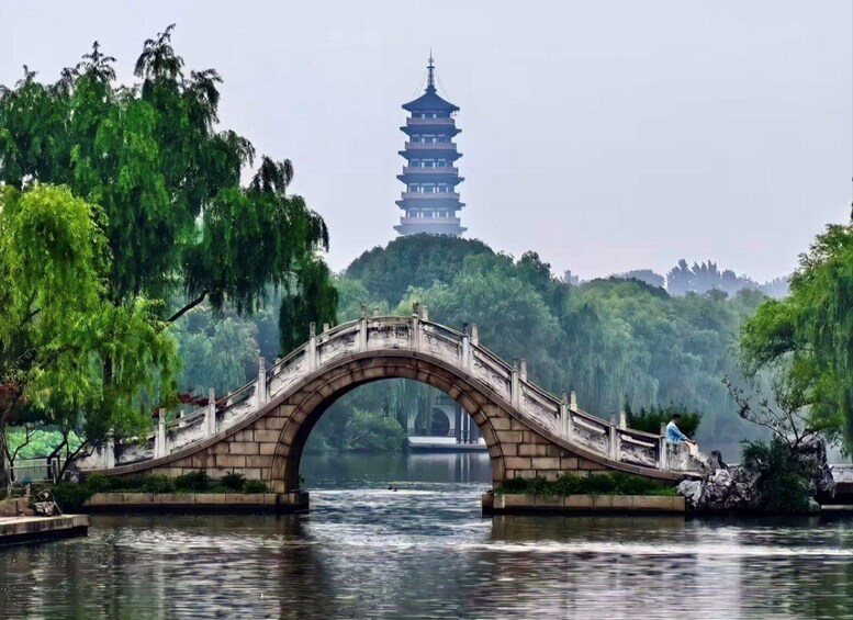 A stone bridge over a river with a pagoda in the background. 2
