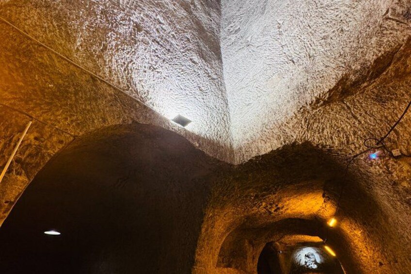 A tunnel with rough, textured walls and a light source at the end. 3