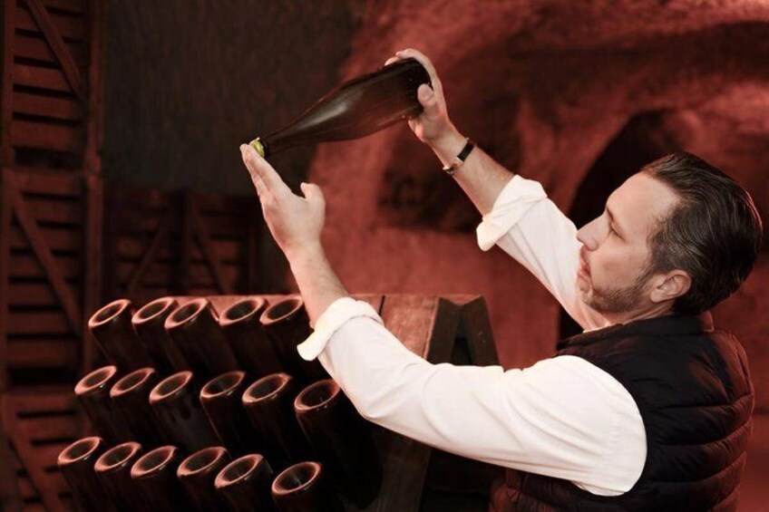 A person pouring a liquid from a bottle into a glass. 1