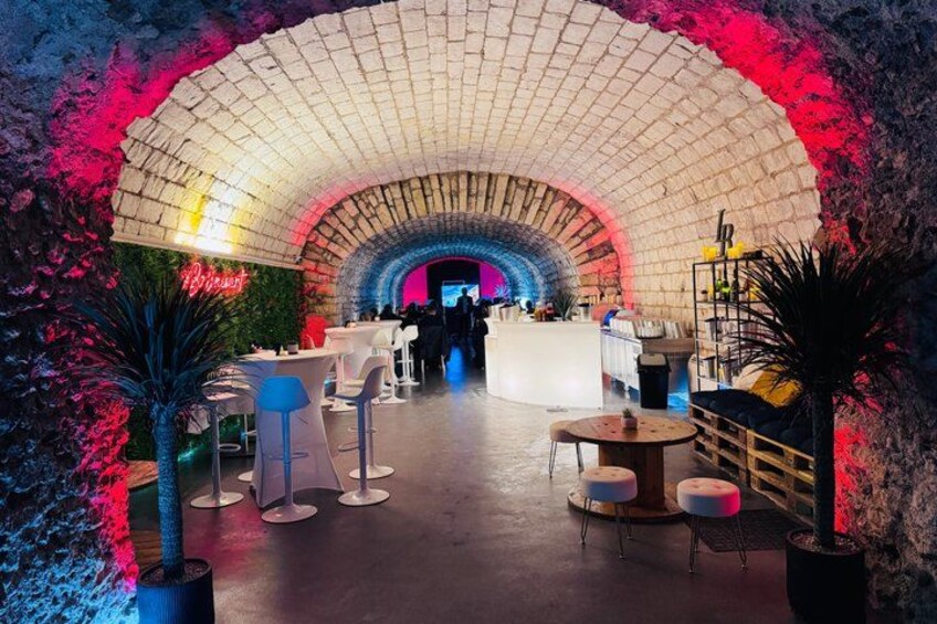An indoor venue with a semi-circular brick ceiling, white tables, and chairs, and potted plants. 5