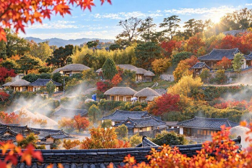 Traditional Korean architecture with thatched roofs, surrounded by autumn foliage. 5