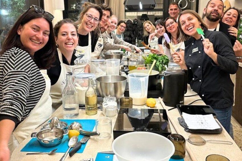 A group of people cooking together in a kitchen, with various cooking utensils and ingredients on the table. 1