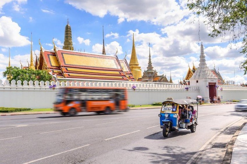 A tuk-tuk on a road with a temple in the background. 2