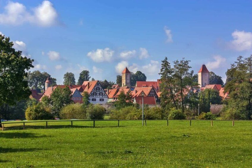 A rural landscape with a traditional half-timbered house and a church with a red roof. 2