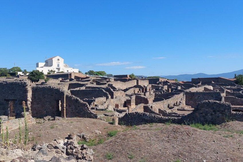 Ancient ruins with scattered buildings and a white church in the background. 5