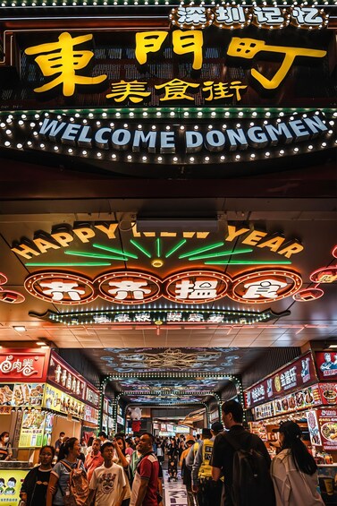 A busy street with neon signs and a crowd of people. 3