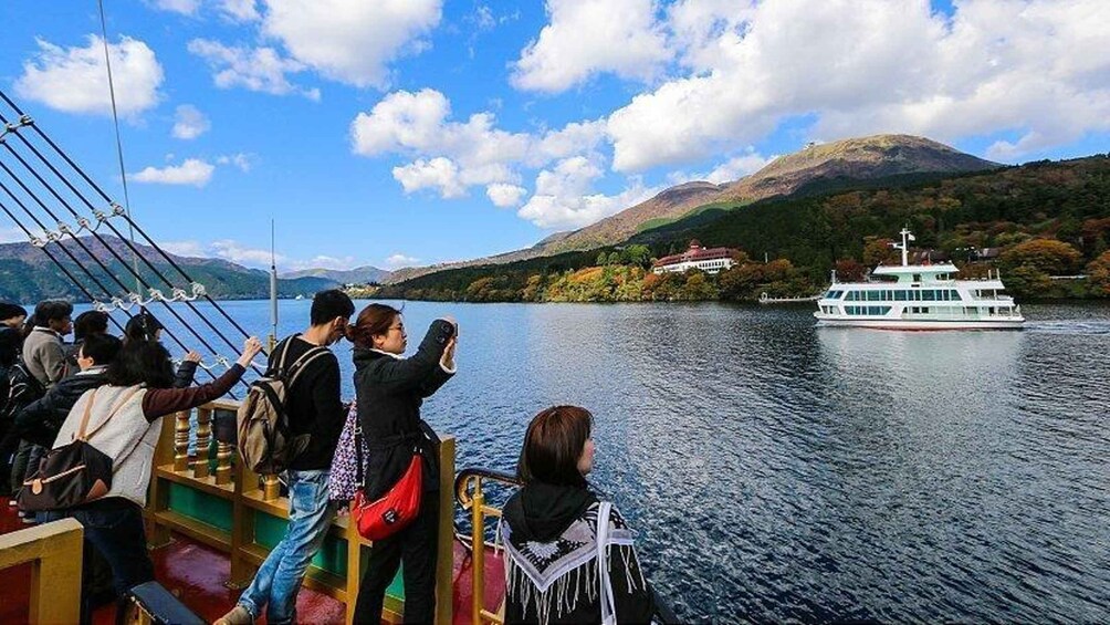 A group of people on a boat, a white riverboat, and a mountainous landscape with autumn foliage. 4