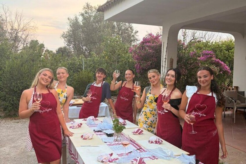 A group of people wearing aprons with a heart logo, standing around a table with a floral tablecloth. 1