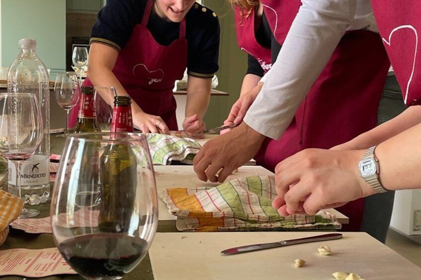 People preparing food, with a bottle of wine and a knife on the table. 4