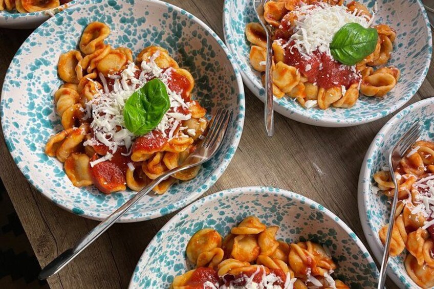 Four bowls of pasta with tomato sauce, grated cheese, and basil leaves. 1