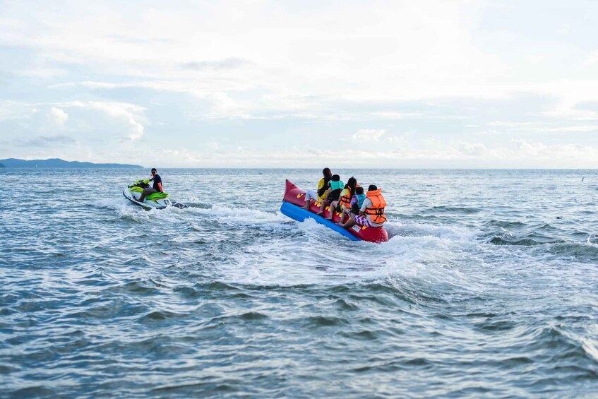 A person riding a jet ski and a group of people on a raft in the ocean. 3