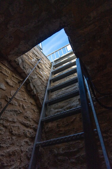 Un escalier métallique qui monte à travers un mur de pierre. 4