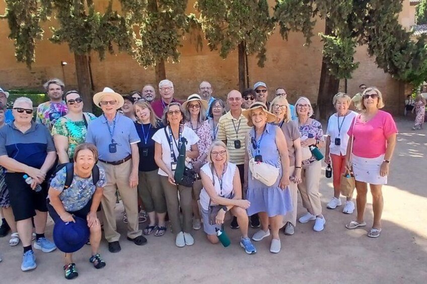 A group of people posing for a photo in an outdoor setting with trees and a building in the background. 3
