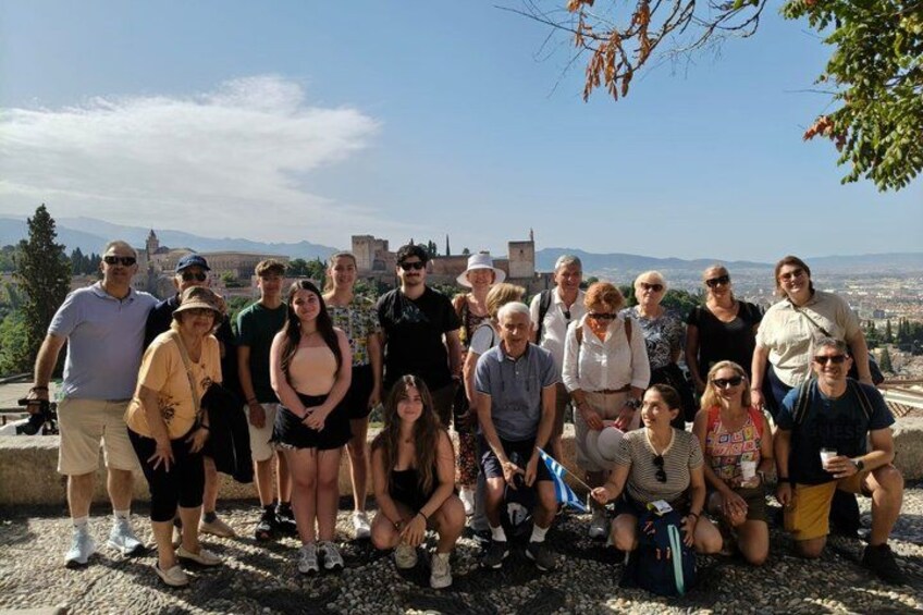 A group of people posing for a photo with a historic building and a cityscape in the background. 2
