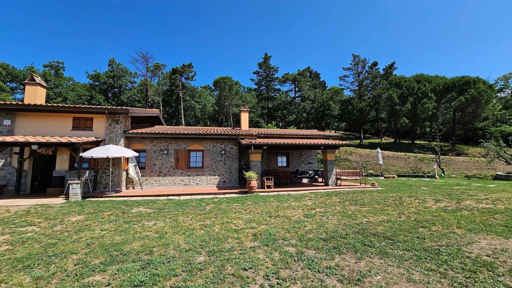 Une maison en pierre avec un toit en tuiles, une terrasse avec des meubles d’extérieur et une cour gazonnée. 1