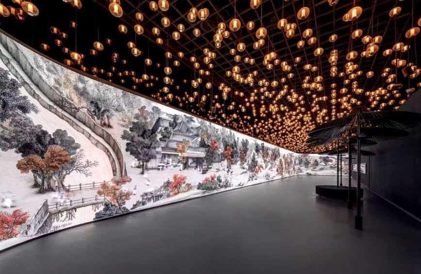 Un couloir orné d’une fresque représentant un paysage traditionnel et éclairé par des lampes sphériques suspendues. 3
