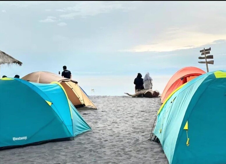 Ein Strand mit mehreren Zelten und blauem Himmel. 3
