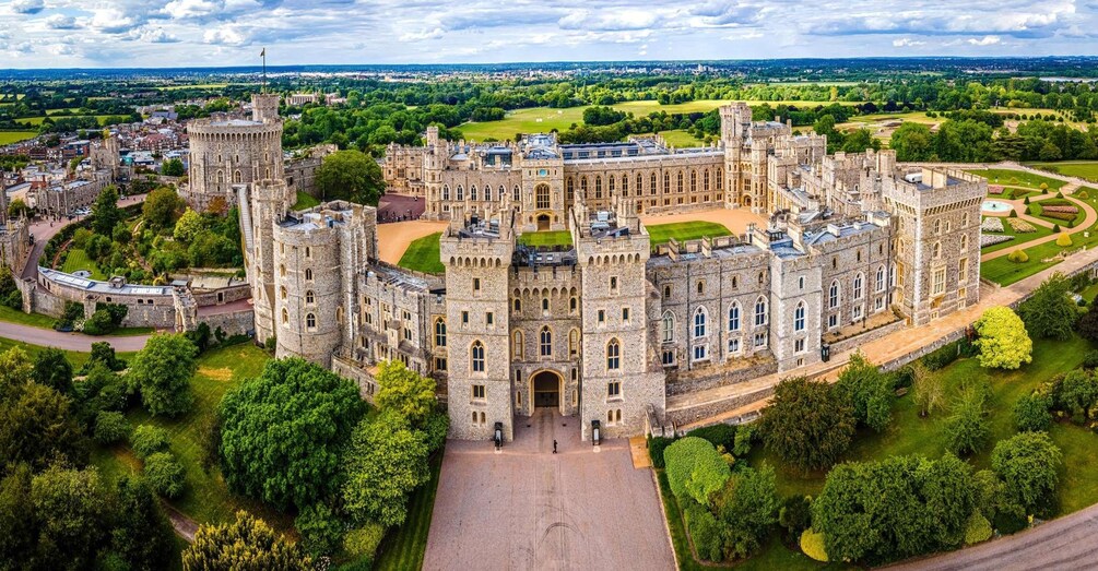 Ein großes, historisches Schloss, umgeben von üppigem Grün und einem gepflegten Rasen. 4
