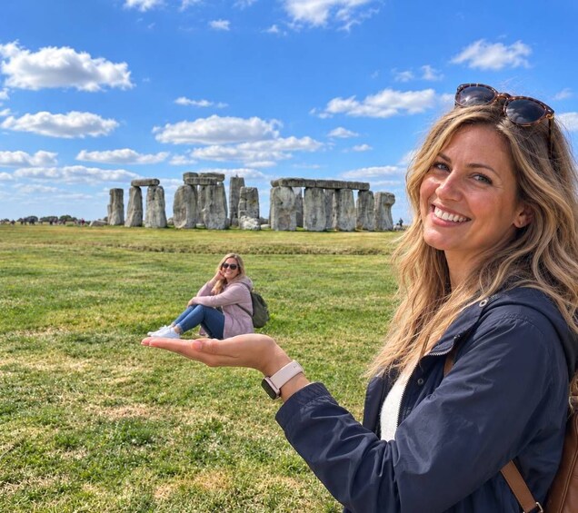 Eine Person hält eine Hand, im Hintergrund eine steinerne Struktur ähnlich wie Stonehenge. 1