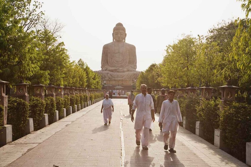 Un sentier mène à une grande statue, où l’on peut s’asseoir, et qui est entourée d’arbres et de constructions traditionnelles. 3