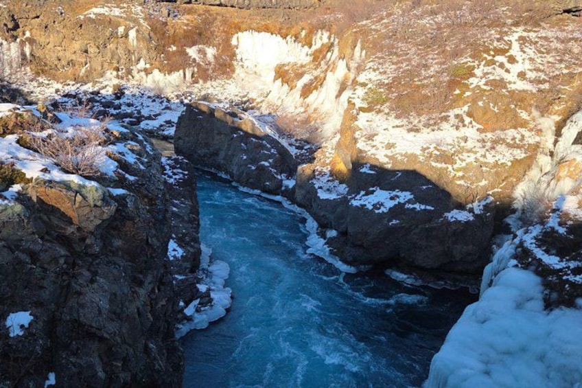 A river flowing through a rocky canyon with snow patches on the rocks and riverbanks. 3