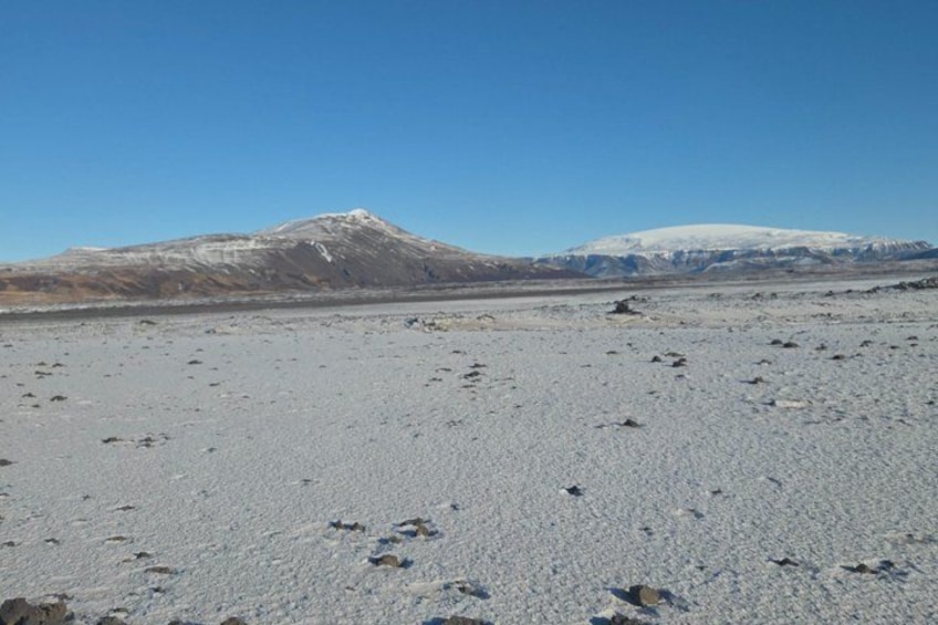A snowy landscape with footprints leading towards a mountain. 2