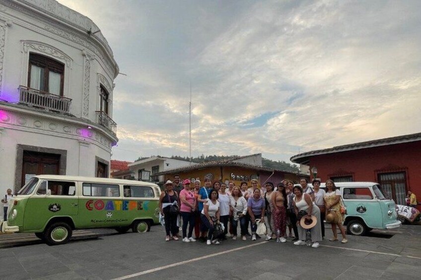 A group of people standing in front of a building with a green and white van parked nearby. 3