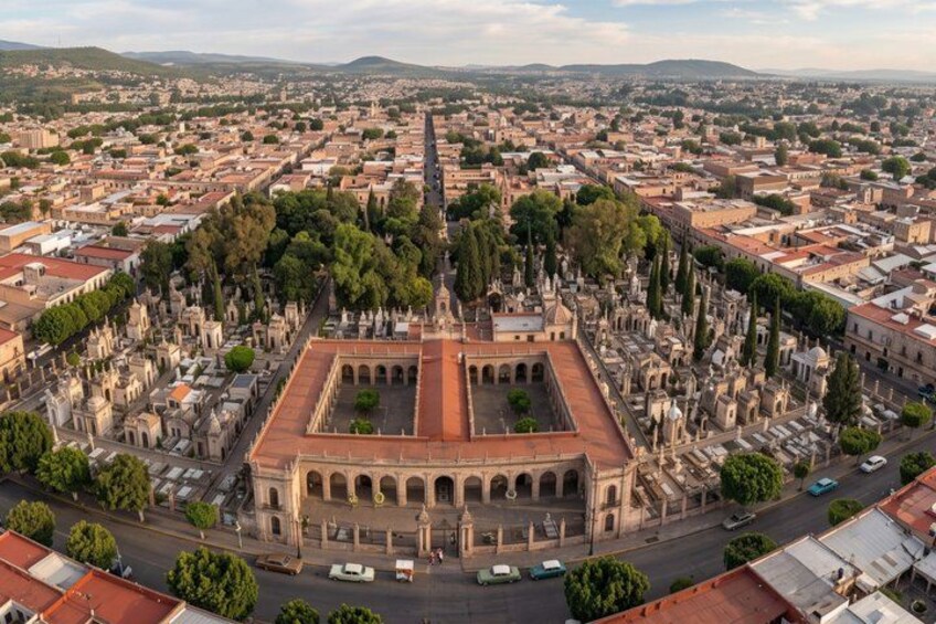 An aerial view of a city with a prominent historical building surrounded by a cemetery. 4