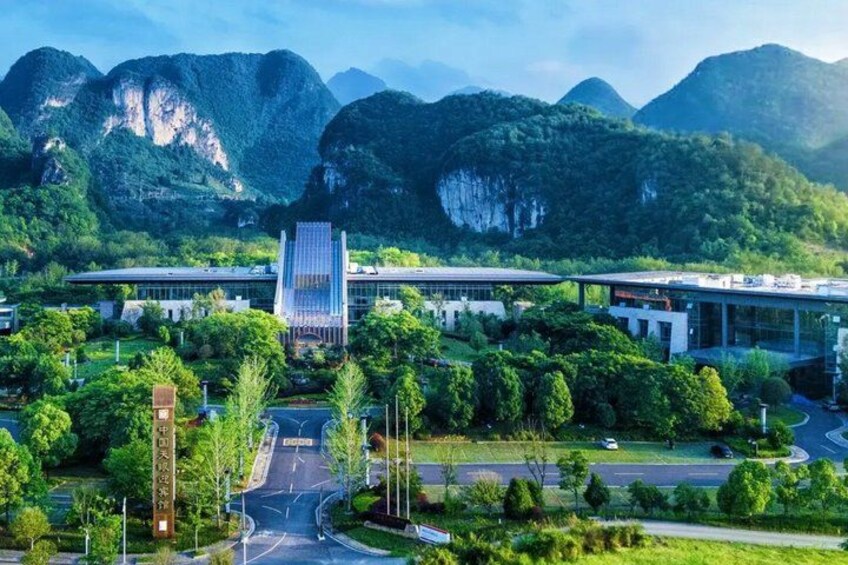 A modern building complex surrounded by lush greenery and mountains. 2