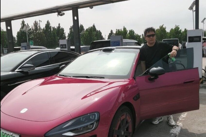 A red sports car at a gas station with a person leaning on the door. 4