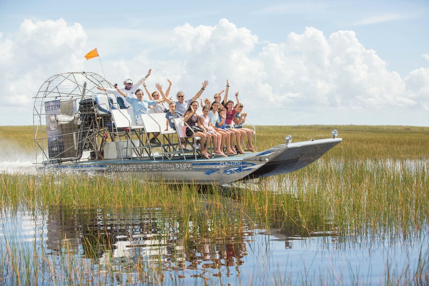 A group of people on a boat in a marshy area with water and tall grasses. 1