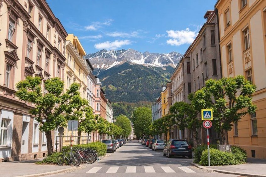 A street with parked cars, bicycles, and buildings with a mountain in the background. 4