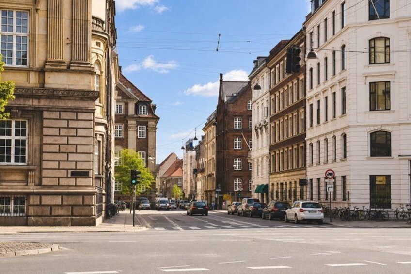 A street lined with historic buildings, a traffic light, and parked cars. 5