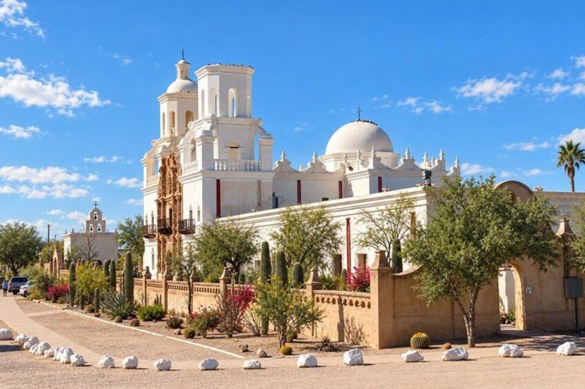 A large white church with domes and bell towers, surrounded by cacti and trees. 4