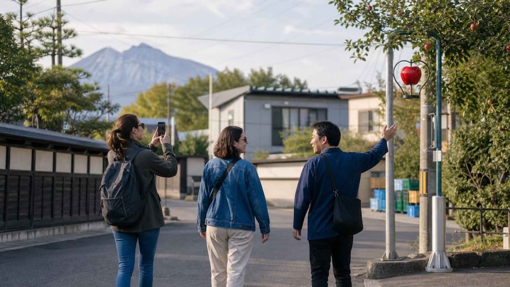 Drei Personen gehen auf einer Straße, im Hintergrund ist ein Berg zu sehen. 1