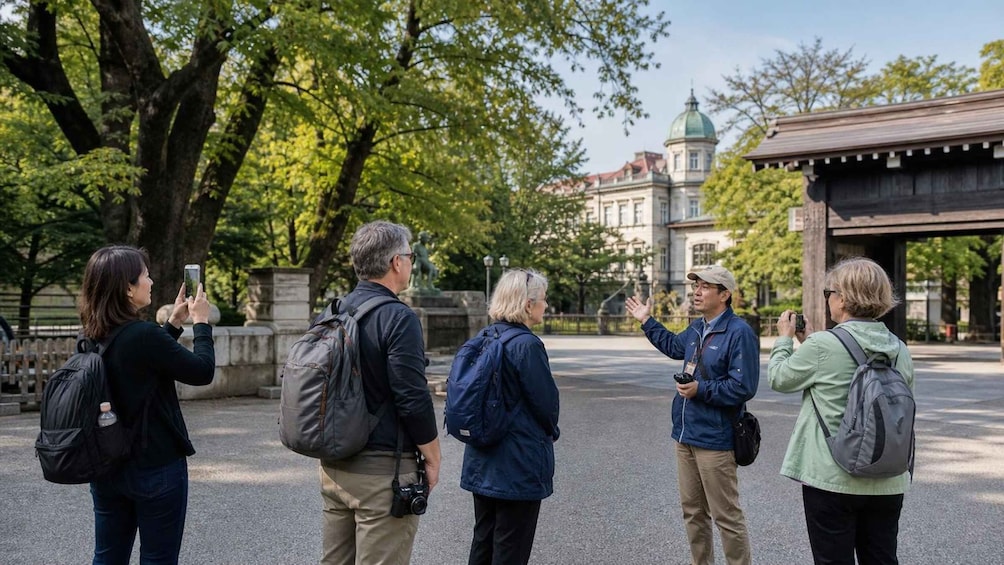 Eine Gruppe von Personen macht Fotos in einem Park mit Bäumen und einem Gebäude im Hintergrund. 4