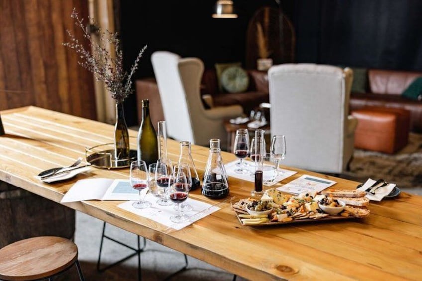A wooden table set with wine glasses, bottles, and a dish of food in a cozy dining area. 5
